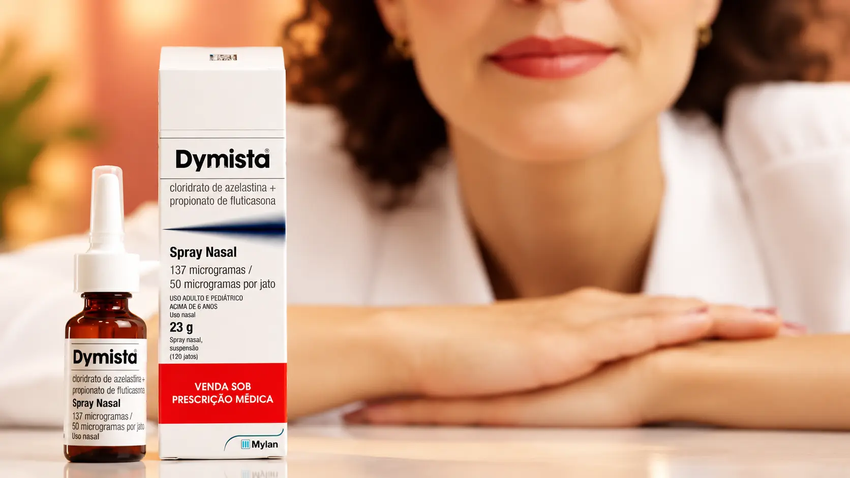 Frasco e caixa do spray nasal Dymista®, com cloridrato de azelastina e propionato de fluticasona, em frente a uma médica de jaleco branco