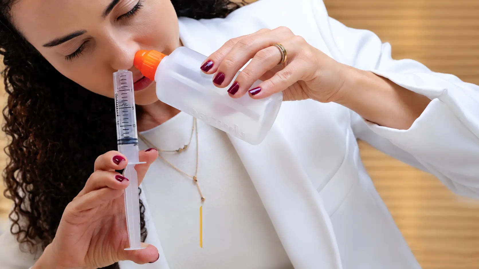 Dra. Larissa Vilela com seringa e garrafinha de lavagem nasal, dispositivos indicados no pós-operatório de cirurgia de nariz