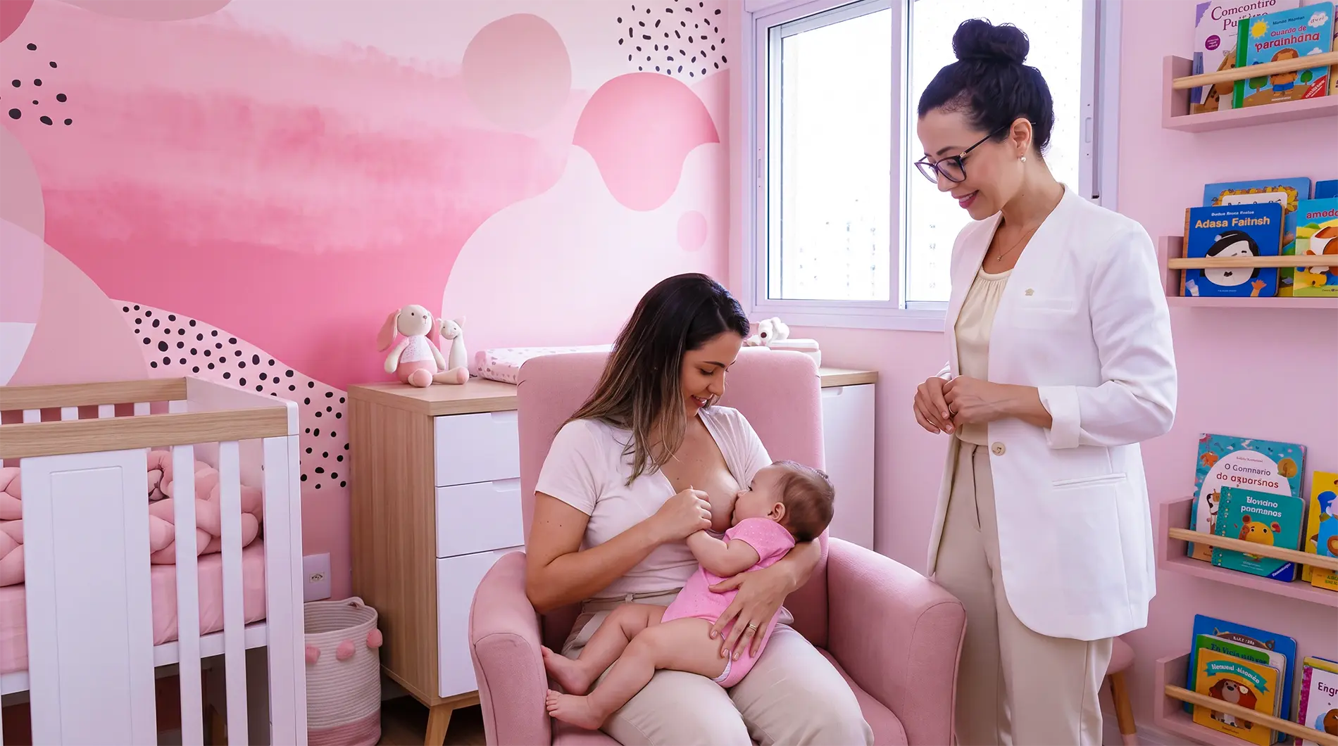 Mãe amamentando bebê em posição inclinada com profissional de saúde ao lado