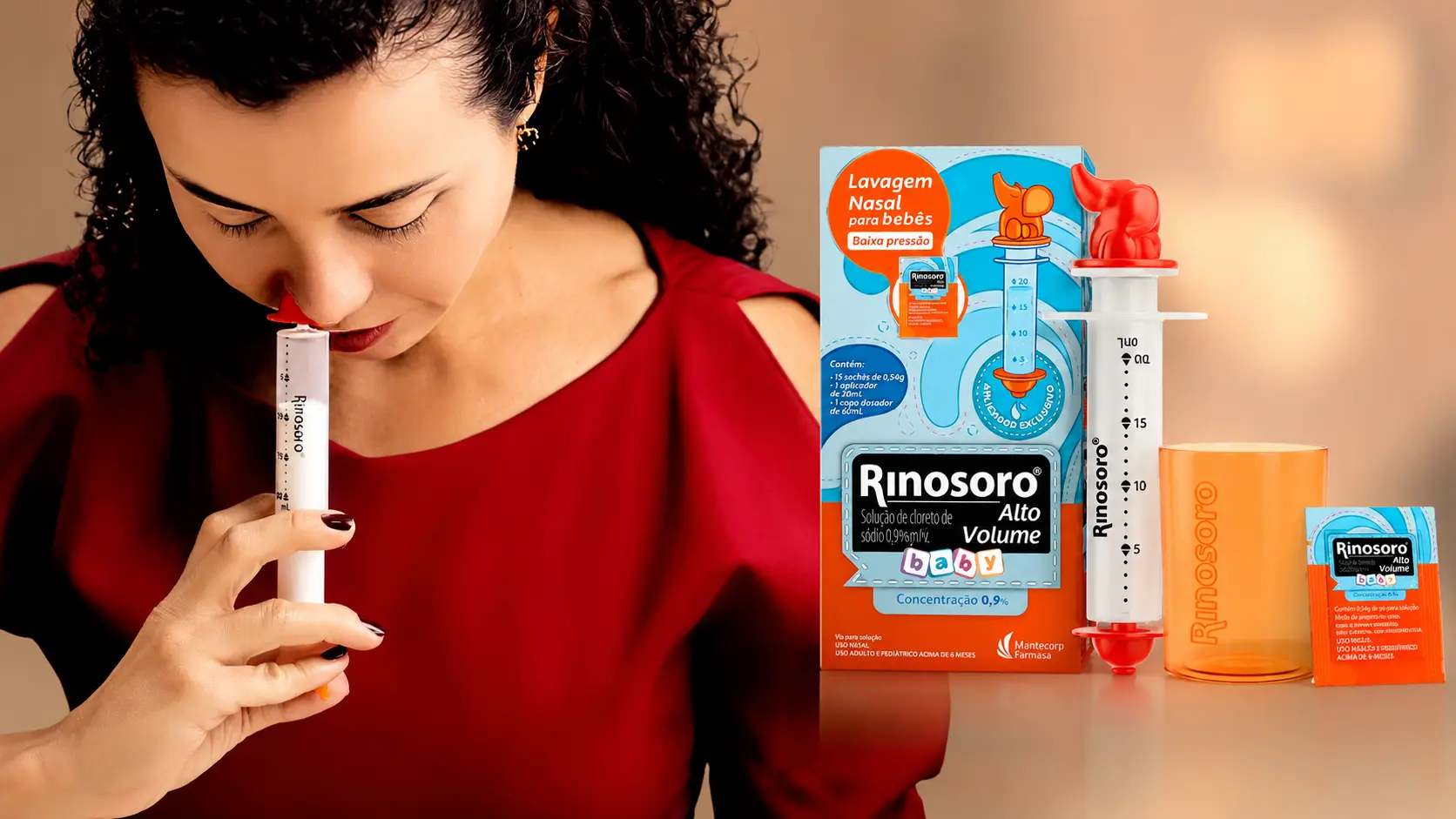 Caixa do Rinosoro Alto Volume Baby ao lado da seringa de 20 mL com bico anatômico, copo dosador e sachê, e mulher fazendo lavagem nasal com o dispositivo
